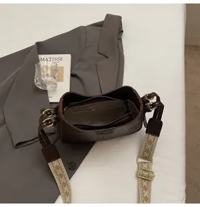 Minimalist dark brown shoulder bag with wide woven strap, premium crossbody bucket bag for women.