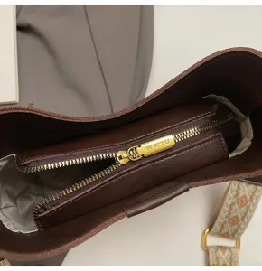 Detailed view of dark brown leather bucket shoulder bag interior zipper pocket hardware