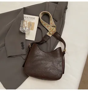 Detailed shot of a stylish dark brown PU leather shoulder bag with a wide woven strap.