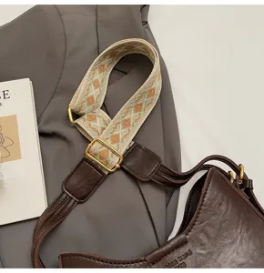 Stylish brown leather shoulder bag featuring a wide ethnic pattern strap, vintage detail.