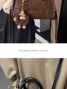 Brown leather crossbody bag detail with cute plush doll keychain and stylish shoulder strap.