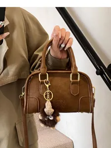 Stylish brown leather top-handle crossbody bag for women featuring cute plush charm and gold hardware.