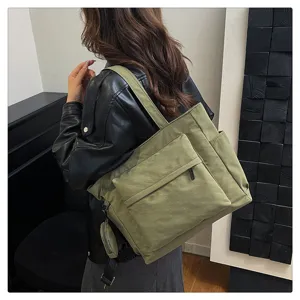 Vista detallada del bolso tote de lona verde oliva con gran capacidad y bolsillo delantero.