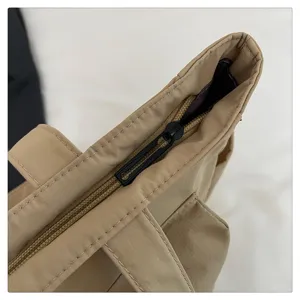 Primer plano del detalle de la cremallera del bolso tote beige con costuras limpias.