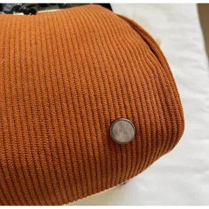 Gros plan détaillé du fond de sac en velours côtelé marron avec pieds de protection en métal.