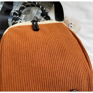 Gros plan détaillé du sac à dos en velours côtelé marron avec une poignée en corde tressée.