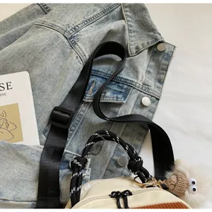 Gros plan détaillé d'un sac de femme stylé avec bandoulière noire et charm en peluche.