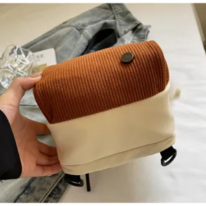 Vue détaillée d'un petit sac à dos bicolore, rabat en velours côtelé marron et corps beige élégant.