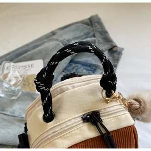 Détail de sac à main en velours côtelé avec poignée en corde noire et fermeture éclair.
