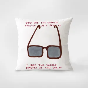 Détail de coussin décoratif artistique avec design de lunettes et citation inspirante.