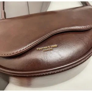 Detailed view of the dark brown leather saddle bag with gold foil text and smooth texture.