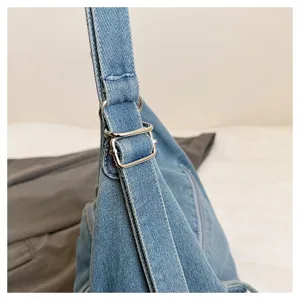 Close-up detail of blue denim shoulder bag strap with adjustable silver metal buckle.