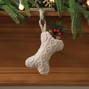 Detailed close-up of a bone-shaped cable-knit Christmas stocking hanging on a festive mantel.