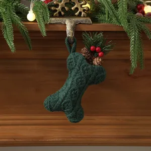 Green knitted bone Christmas stocking holiday decor with pinecones and berries for tree.