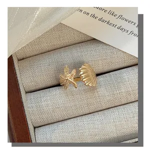 Detail view of gold starfish and seashell open ring, highlighting fine ocean theme.