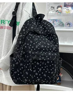 Detailed view of black corduroy backpack with cute white heart and bow prints for daily use.