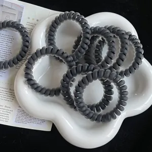 Close-up van matzwarte telefoonkoord haarbanden, spiraalvormige elastische haaraccessoires.
