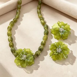 Green resin flower necklace and earrings set close-up view, elegant resort fashion jewelry details.