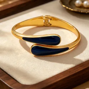 Detail shot of a fashion alloy open bangle bracelet featuring elegant dark blue enamel drop ends.