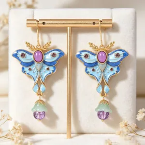 Close-up of vintage blue enamel moth earrings with purple crystal tassel detail.