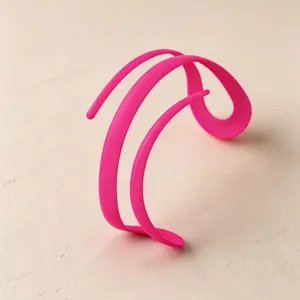 Closeup of minimalist candy pink abstract cuff bracelet, unique curved design matte detail view