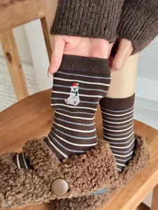 Close-up detail of cute polar bear embroidery on brown striped winter warm wool socks.