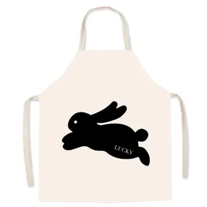 Detail view of beige kitchen apron with black jumping rabbit graphic and lucky print.