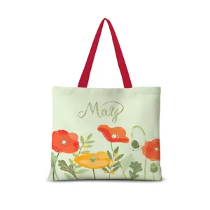 Vue détaillée du sac cabas en toile montrant l'imprimé floral et les anses rouges en gros plan.