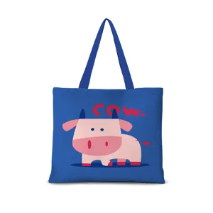 Sac cabas en toile bleue avec illustration de vache de dessin animé et impression rouge.