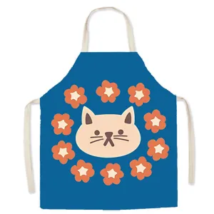 Close-up detail of the cute cat face and flower pattern on blue kitchen apron fabric.