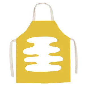 Detailed shot of yellow Nordic style kitchen apron with white abstract graphic print and straps.