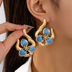 Detailed shot of irregular geometric blue enamel flower earrings, elegant gold design for women.