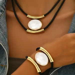 Detailed view of retro multi-layer black cord necklace and bracelet set with white oval pendant.