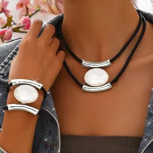 Multi-layer black cord necklace and bracelet set with silver metal bars and oval white pendant.