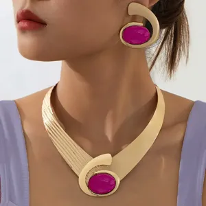 Chunky gold statement necklace and earrings set with vibrant magenta resin stones, vintage design.