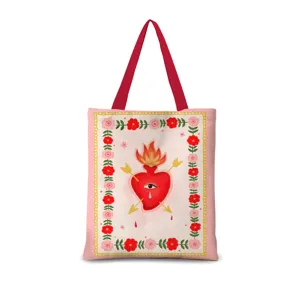 Détail de sac cabas en toile rose avec un superbe motif de cœur sacré et anses rouges.