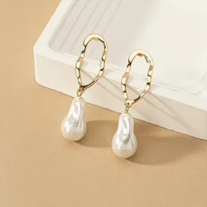 Boucles d'oreilles géométriques dorées minimalistes avec pendentifs perles baroques.