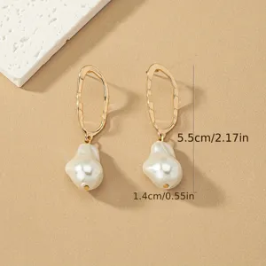 Vue de détail rapprochée de boucles d'oreilles géométriques dorées avec perles baroques.
