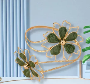 Detail shot of the stylish gold metal arm cuff featuring hollow green floral pattern design.