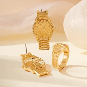 Detail shot of gold watch shaped jewelry set including earrings and ring with roman numerals.