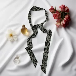 Detailed view of a trendy leopard print long narrow silk scarf choker neck band accessory.