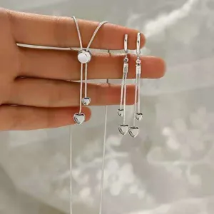 Close-up detail of silver long tassel necklace and matching heart earrings set sparkling.