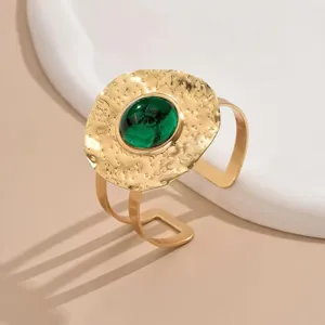 Detail view of gold hammered open cuff bracelet featuring a green gemstone and chic crinkle design.