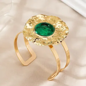 Close-up of the hammered gold open cuff bracelet featuring a striking central green dome gemstone.