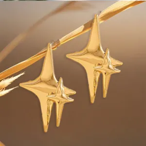 Close-up of shiny gold geometric abstract star earrings displayed on natural straw.