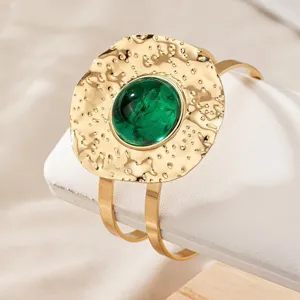 Detailed shot of the gold geometric textured cuff bracelet featuring a striking green center stone.