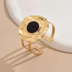 Close-up of the hammered gold cuff bracelet showing textured circular design and black inlay.