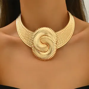 Close-up detail of a vintage gold-tone statement choker necklace with a geometric swirl motif.