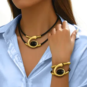 Close up detail of women boho spiral gemstone necklace and bracelet jewelry set in gold black.