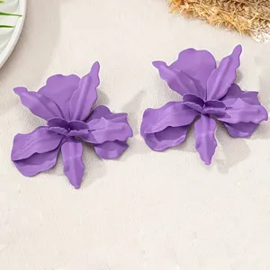 Gros plan détaillé de boucles d'oreilles fleurs en métal laqué violet avec design plissé.